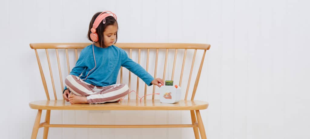 child sitting on a bench and listening to the Yoto player