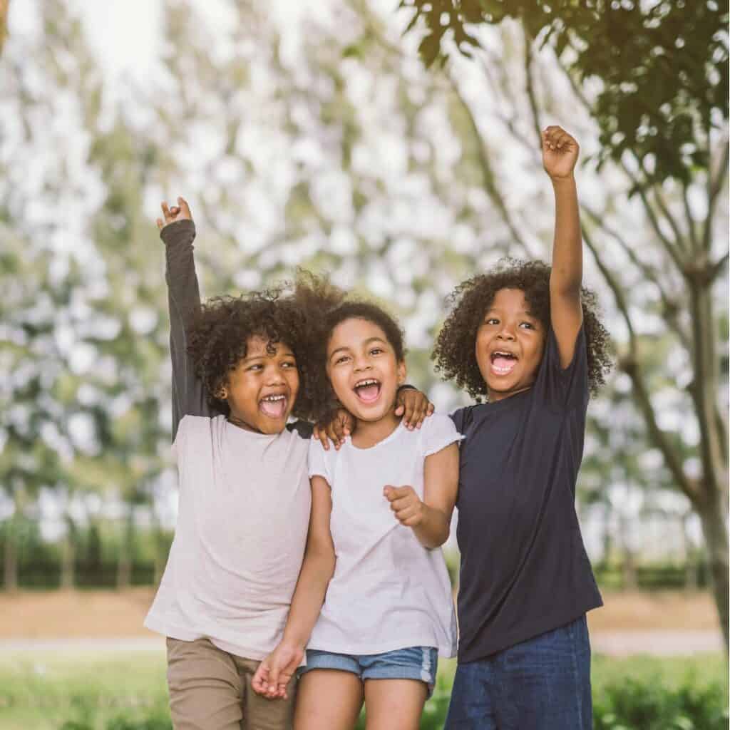 three children cheering and fist pumping the air celebrating being bilingual kids in the USA