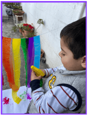 Boy spraying water onto rainbow colored crepe paper