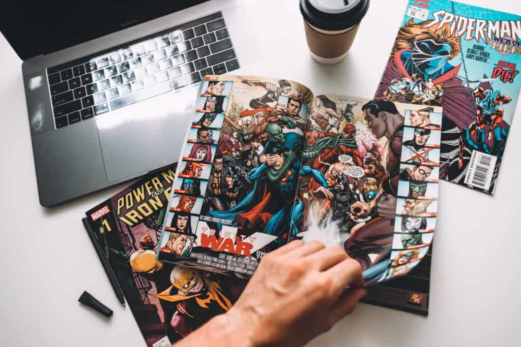 open spiderman comic book next to a laptop and cup of coffee