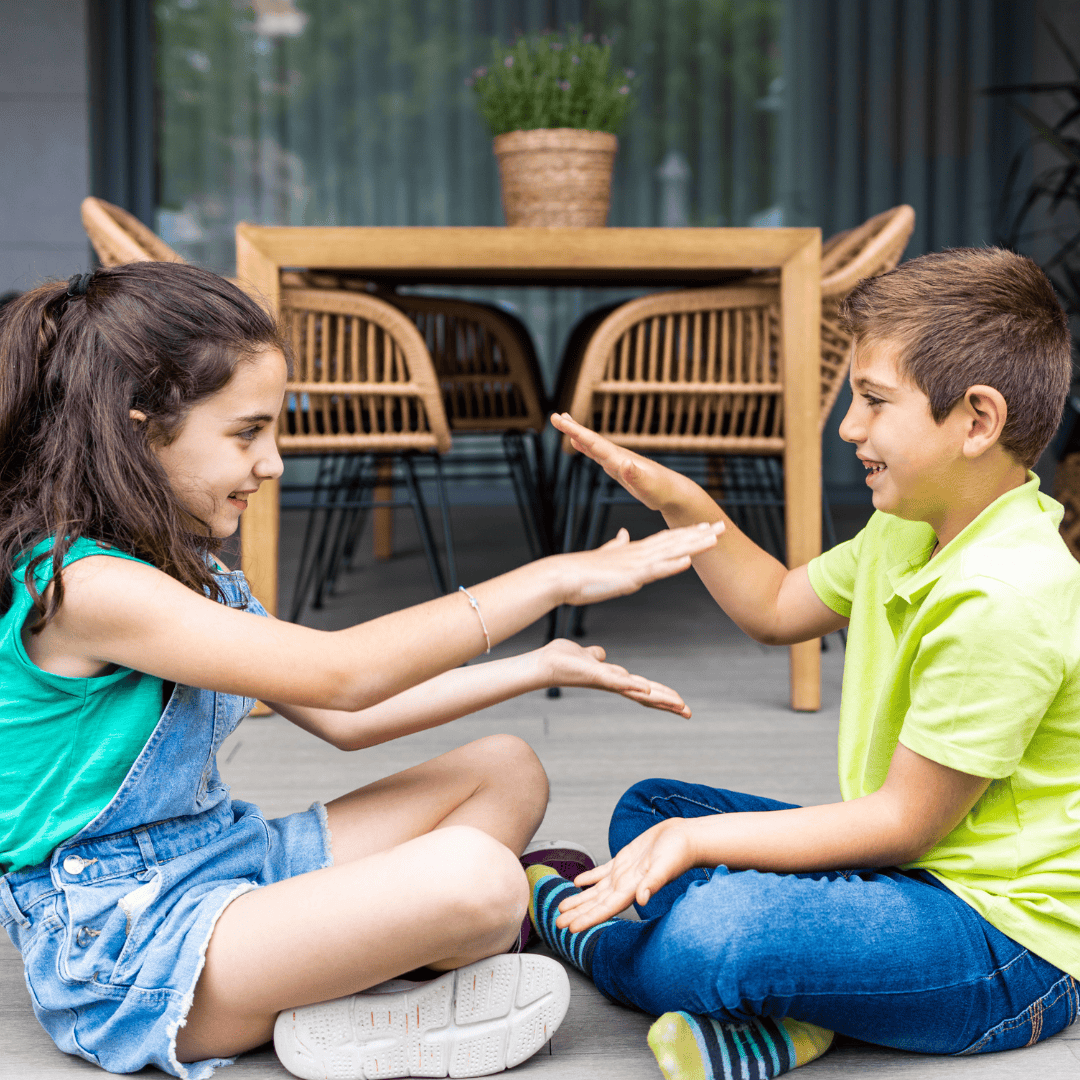 a boy and girl playing a hand clapping game